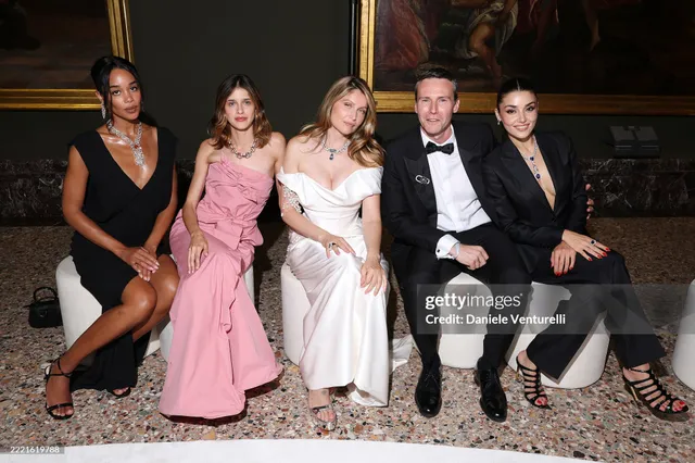 Hande Erçel sitting with guests in a black suit and heels.