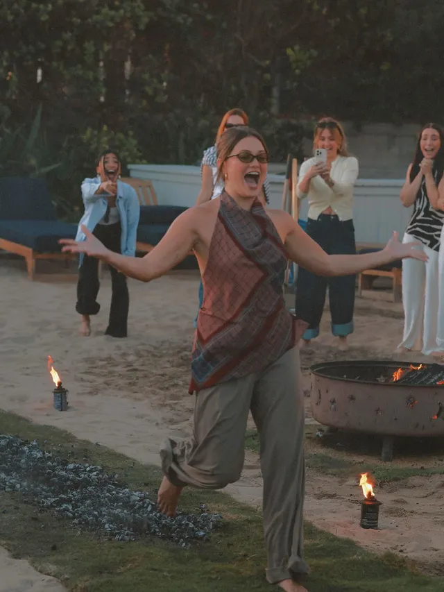 Olivia Holt standing barefoot with a group outdoors in a scene.