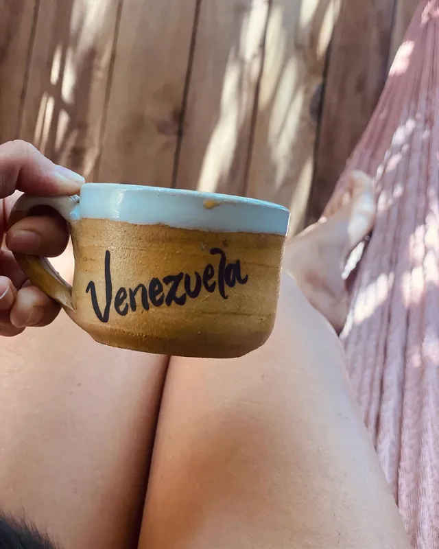 María Gabriela de Faría holding a mug while relaxing in a hammock.
