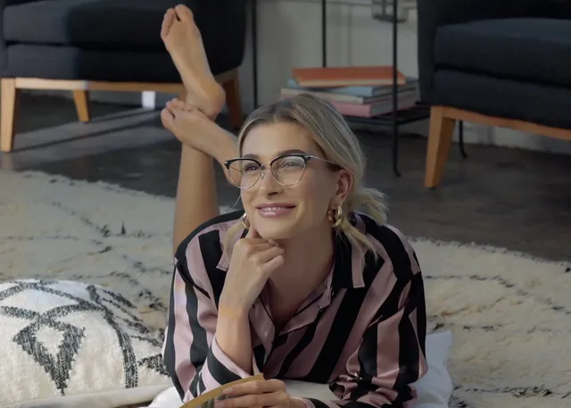 Hailey Bieber lying on a rug with bare feet raised.
