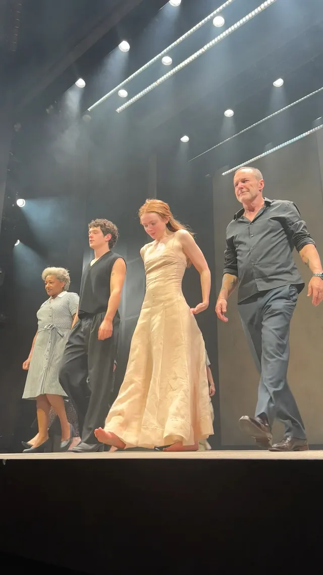 Sadie Sink standing barefoot with other performers at a curtain call.