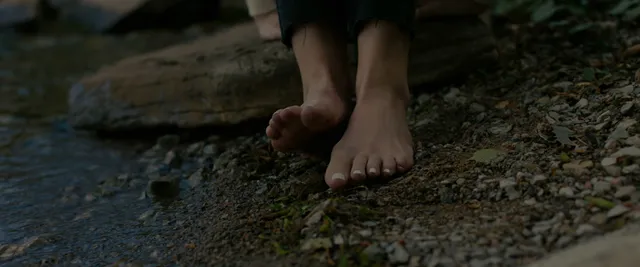 Anna Kendrick showing bare feet on a forest floor.