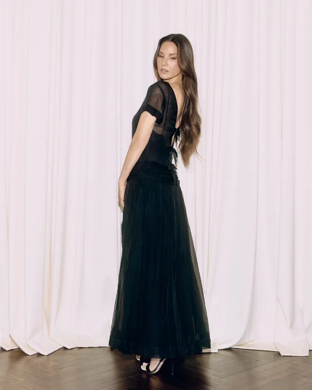 Olivia Munn posing in a flowing black dress and heels.