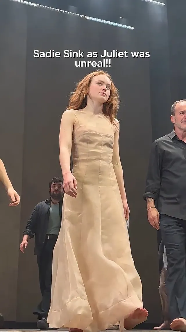 Sadie Sink walking barefoot onstage in a pale dress.