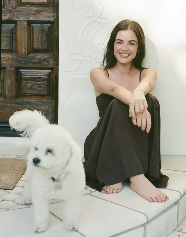 Lucy Hale sitting beside a white dog on a tiled porch.