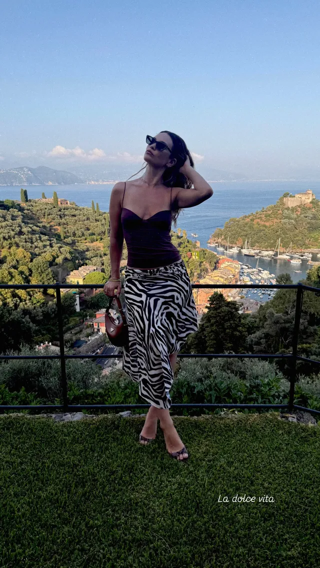 Lily James standing barefoot on a lawn overlooking the coast.