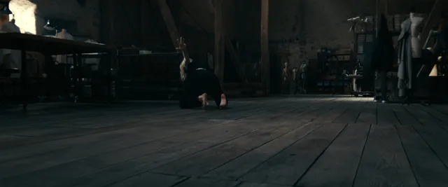 Anne Hathaway standing on a dark street in a screen scene.