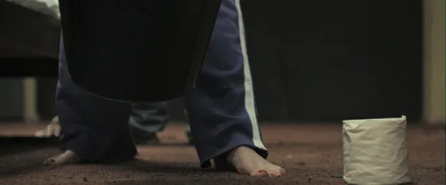 Gemma Arterton standing beside a bucket in purple trousers in a screen scene.