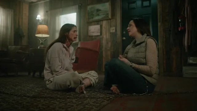 Elizabeth Gillies sitting with a companion during a screen scene.