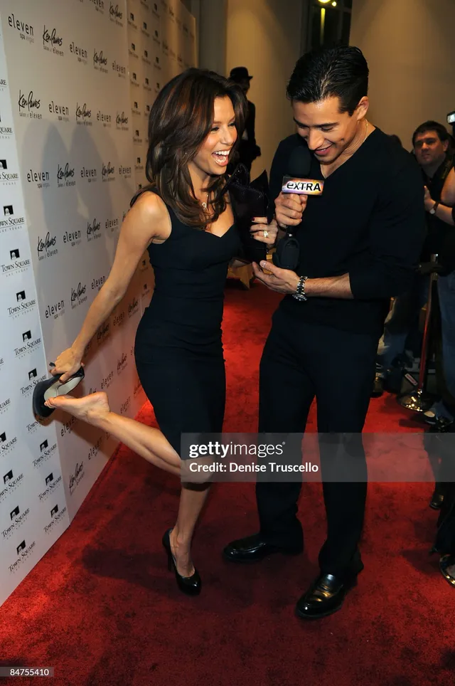 Eva Longoria lifting a bare foot during a red carpet interview.
