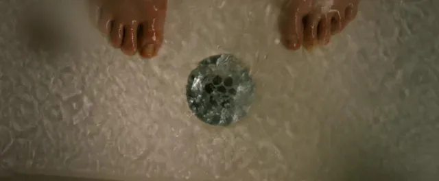Natalie Dormer standing beside a drain in a screen scene.
