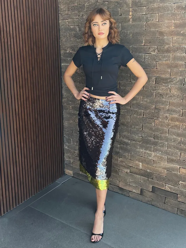 Ella Purnell standing beside a brick wall in a sequinned skirt.