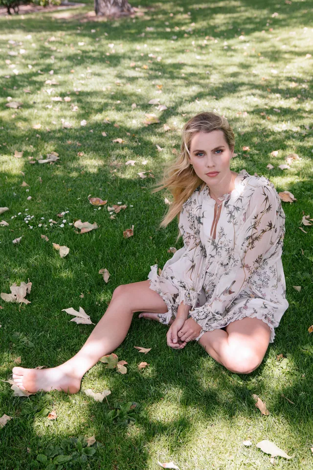 Claire Holt sitting on grass in a patterned robe.