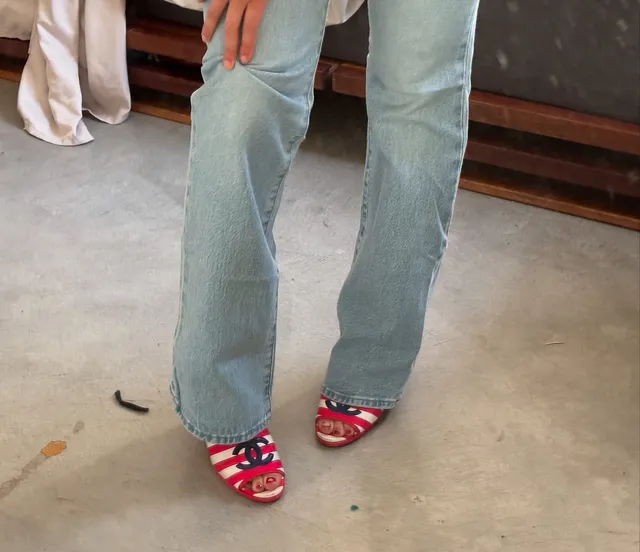 Dafne Keen showing red open toe heels beneath wide leg jeans.