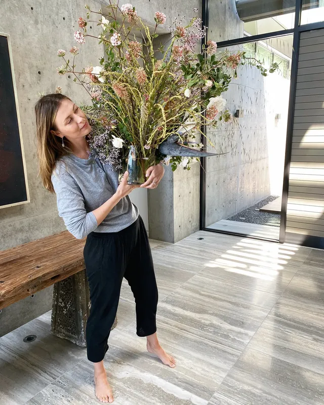 Maria Sharapova standing barefoot on a wooden floor while arranging flowers.