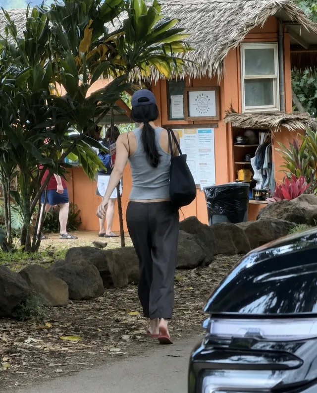 Kendall Jenner walking along a tropical path in casual sandals.