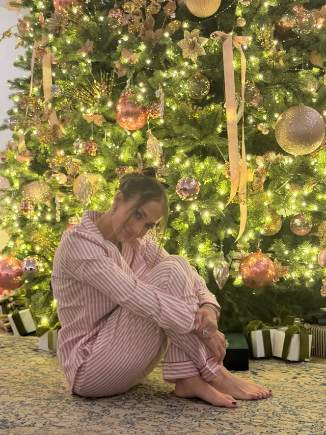 Jennifer Lopez striped pyjamas beside a Christmas tree.