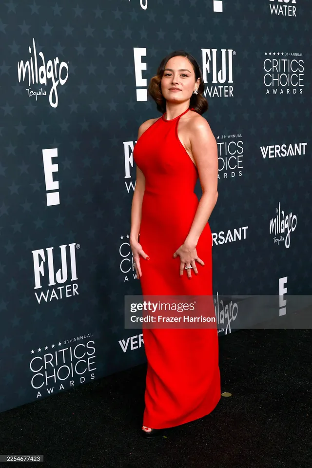 Chase Sui Wonders wearing a red gown and heels at an awards event.