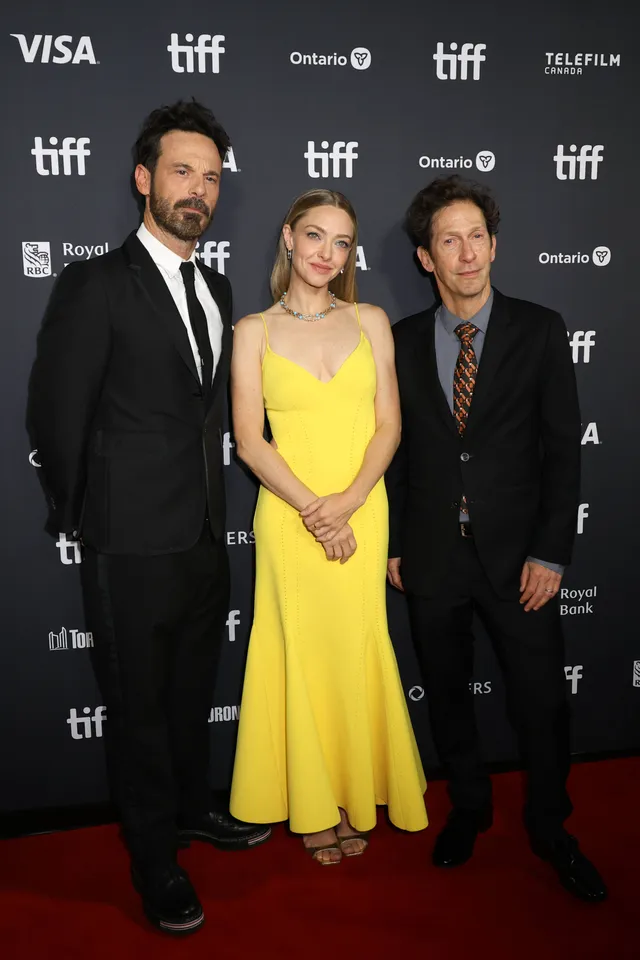 Amanda Seyfried posing with other guests in a yellow dress and open-toe heels.