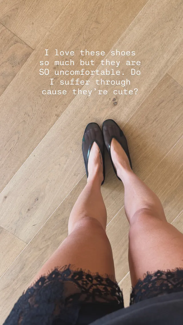 Claire Holt a close-up of black flat shoes on a wooden floor.