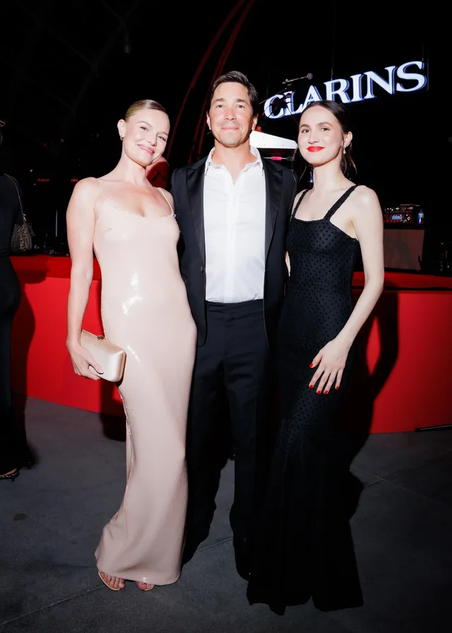 Kate Bosworth posing with guests in a pale gown.