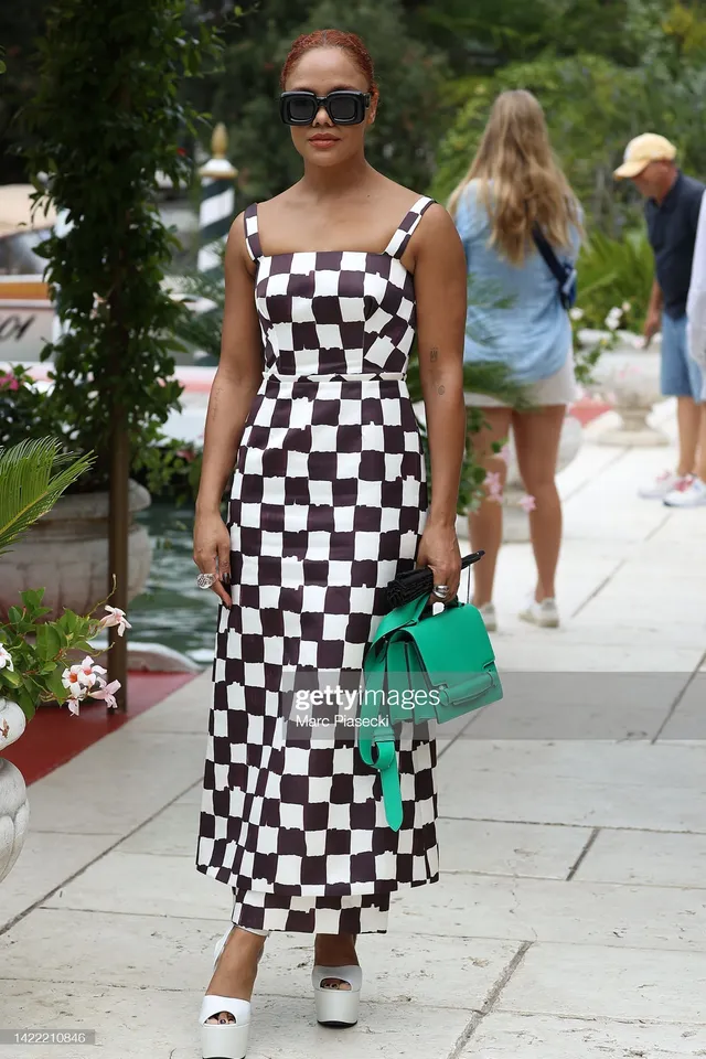 Tessa Thompson walking outdoors in a checked dress and white platforms.