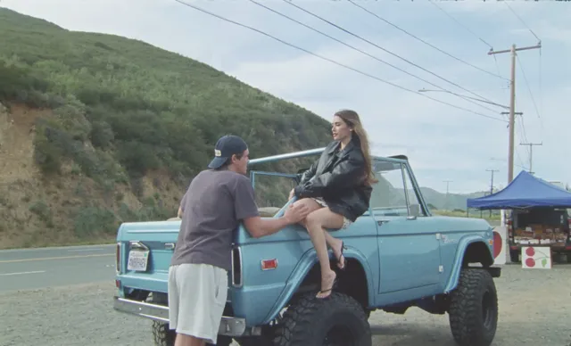 Madison Beer sitting beside a man on a blue vehicle wearing heels.