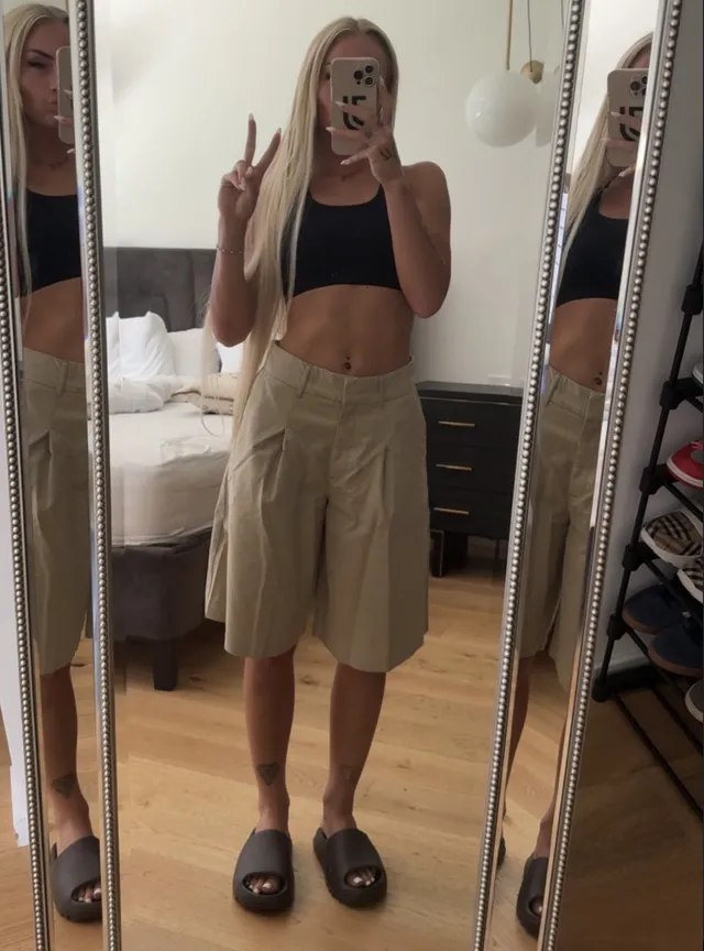 Alisha Lehmann taking a mirror photograph in dark flat slides and a casual outfit.