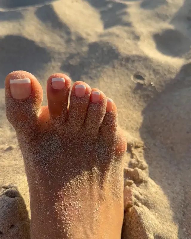 Shay Mitchell a close-up of sandy toes on a beach.