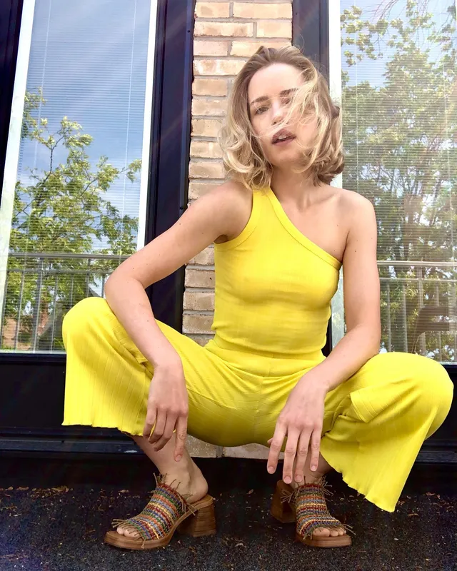 Willa Fitzgerald crouching in a yellow outfit and block heels.