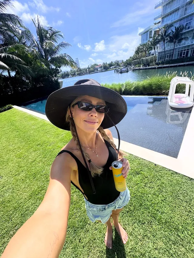 Claire Holt taking a selfie beside a swimming pool.