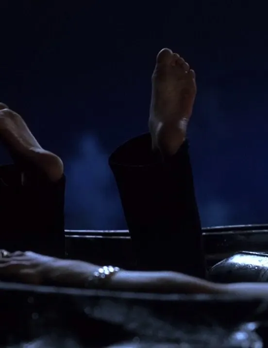 Anne Hathaway raising a bare sole in a dark screen scene.