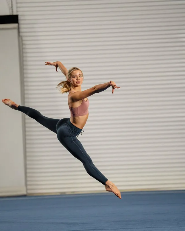 Olivia Dunne jumping barefoot during a gymnastics training session.
