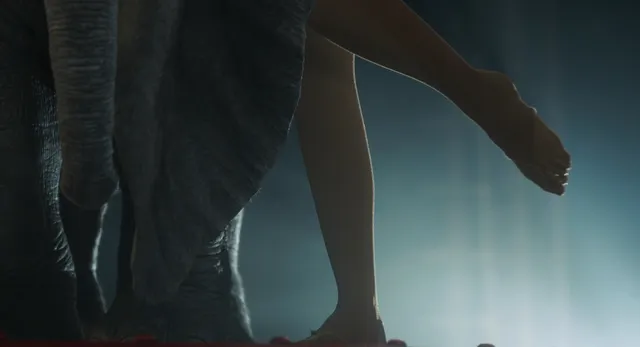Eva Green showing bare feet while seated in a dim film scene.