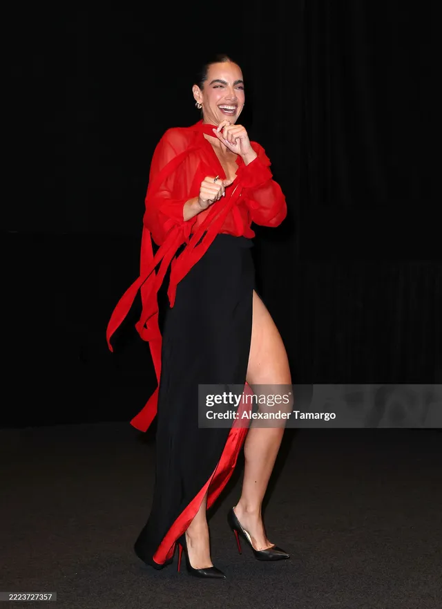 María Gabriela de Faría posing in a red top and black heels.