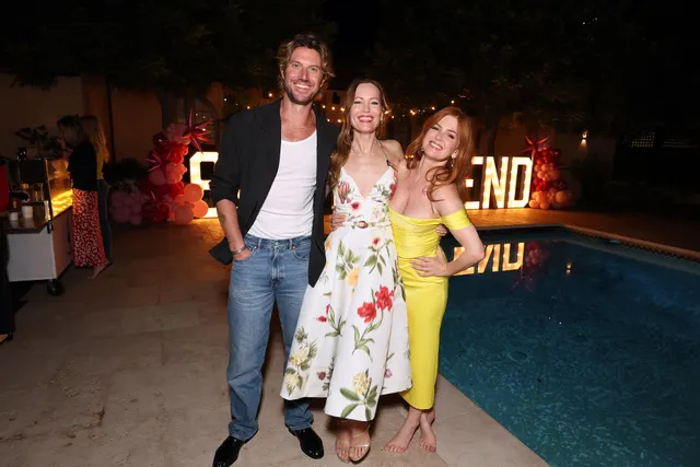 Isla Fisher standing with companions at an evening gathering.