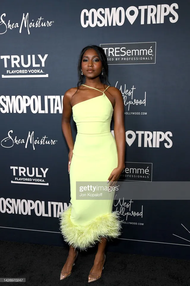 Carlacia Grant wearing a yellow feather-trimmed dress and pointed heels at an event.