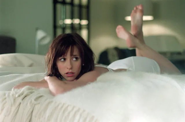 Jennifer Love Hewitt lying on a bed with her bare soles raised.