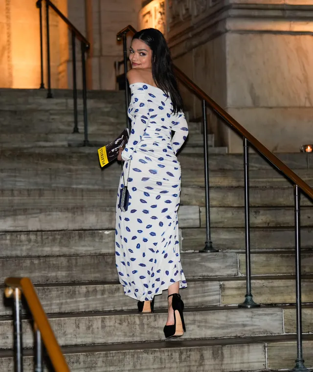 Rachel Zegler descending steps in a patterned dress and black pumps.
