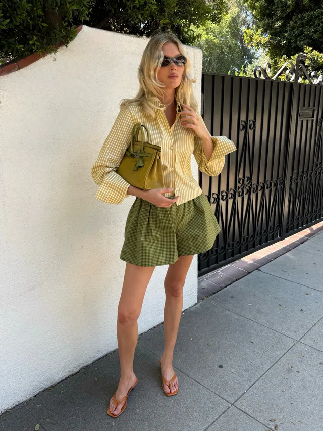 Elsa Hosk wearing pale flat sandals with green shorts and a yellow blouse.