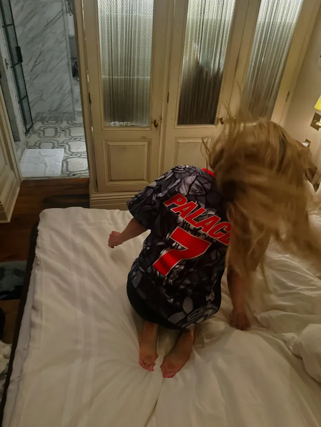 Ellie Goulding kneeling on a bed with bare soles visible.