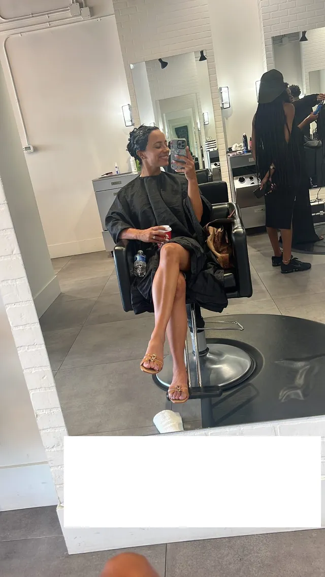 Kiana Madeira sitting barefoot in a salon chair for a mirror selfie.
