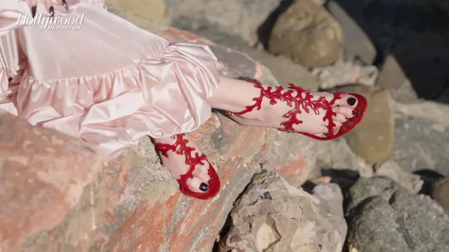 Anya Taylor-Joy wearing red embroidered slippers with a satin outfit.