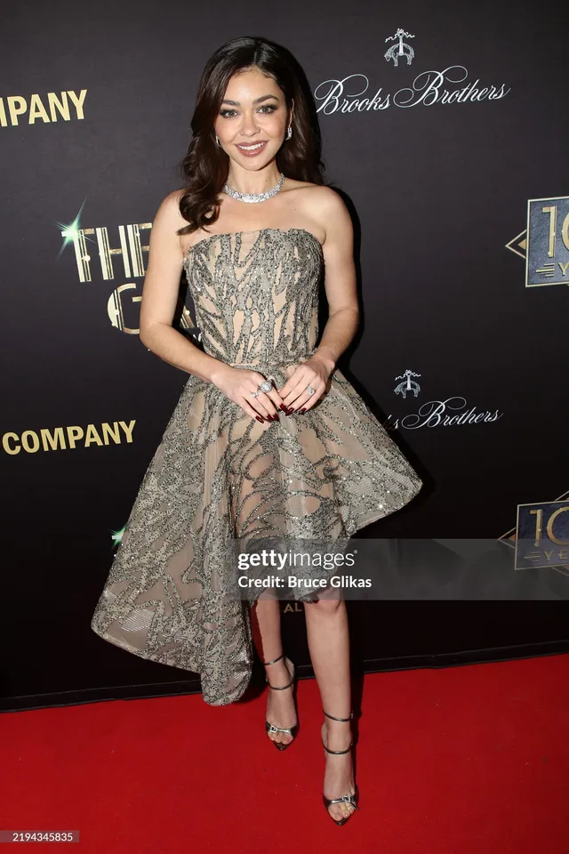 Sarah Hyland standing on a red carpet in a patterned dress.