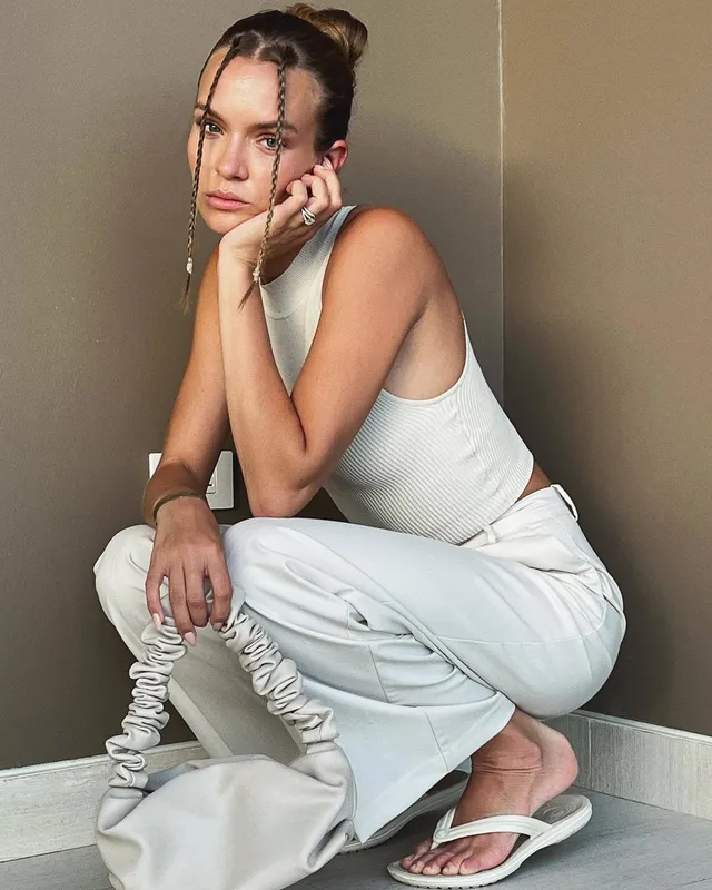 Josephine Skriver crouching in white flat sandals during a studio portrait.