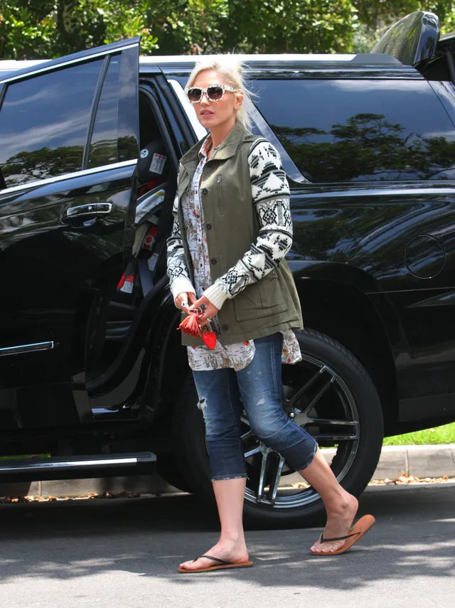 Gwen Stefani walking outdoors in rolled jeans and flip-flops.
