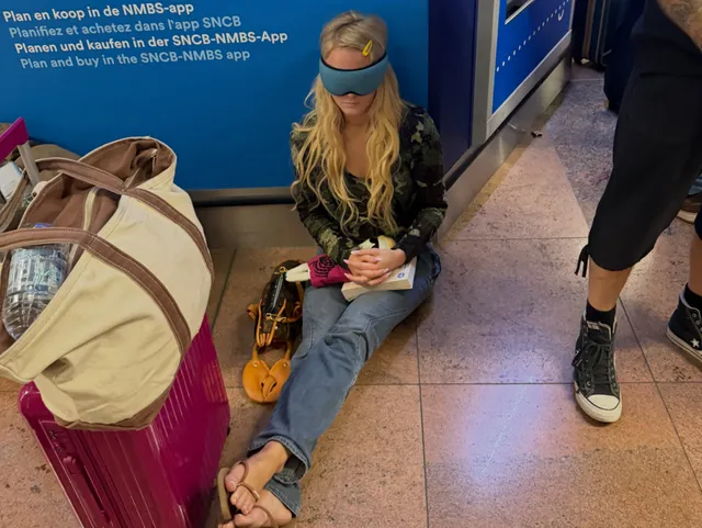 Zara Larsson sitting barefoot beside luggage at an airport.