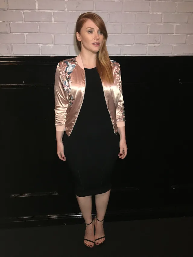 Bryce Dallas Howard posing indoors in a short black outfit.