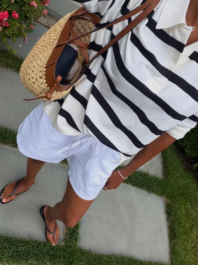 Jasmine Tookes wearing flat sandals with white shorts and a striped top.
