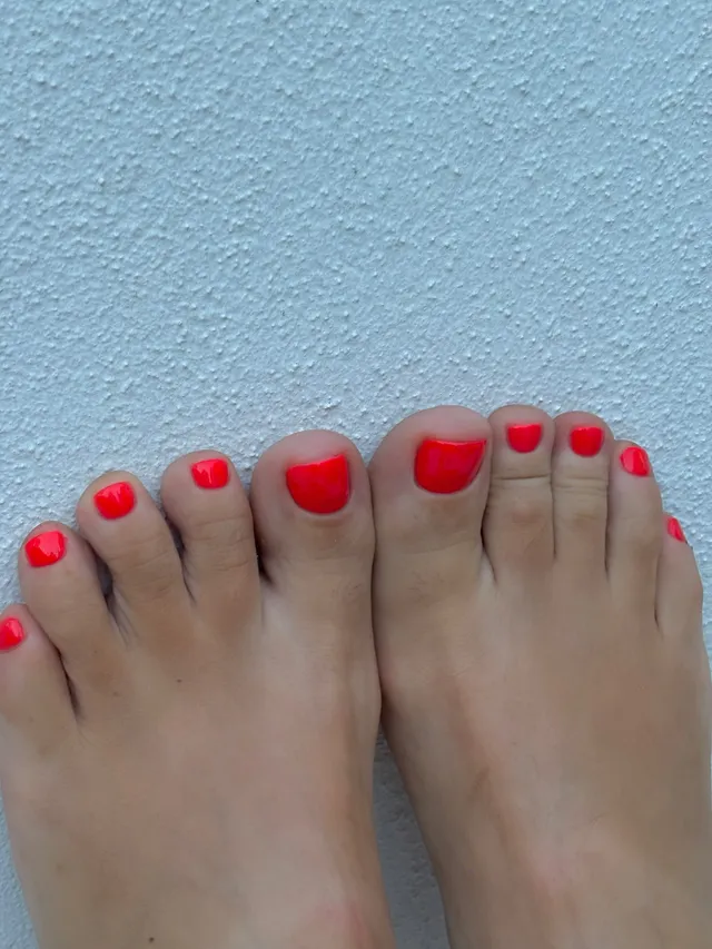 Lily Allen: close view of red-painted toenails against a blue background.